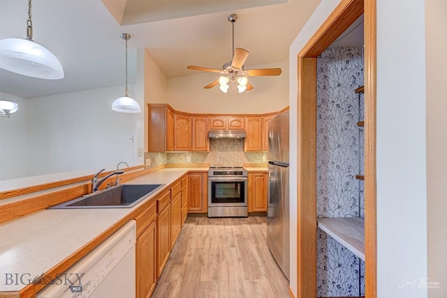 513 Burnham Pl, Helena, MT 59601 - kitchen with appliances with stainless steel finishes, light wood-style floors, light countertops, under cabinet range hood, and tasteful backsplash
