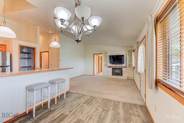 513 Burnham Pl, Helena, MT 59601 - kitchen with freestanding refrigerator, a fireplace, light wood finished floors, a chandelier, and a breakfast bar area