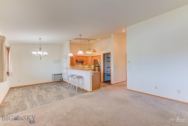 513 Burnham Pl, Helena, MT 59601 - kitchen featuring freestanding refrigerator, a peninsula, under cabinet range hood, a breakfast bar, and a chandelier