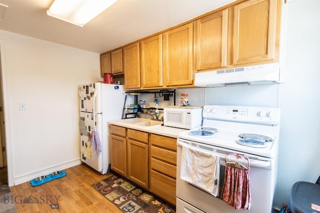 721 W Park Ave, Anaconda, MT 59711 - kitchen featuring white appliances, under cabinet range hood, light wood-style floors, and light countertops