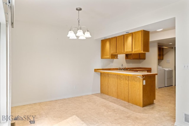 605 Prairie Ave, Bozeman, MT 59718 - kitchen with washer and dryer, a chandelier, a peninsula, decorative light fixtures, and brown cabinets