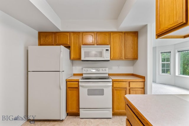 605 Prairie Ave, Bozeman, MT 59718 - kitchen featuring white appliances, light countertops, brown cabinetry, and a raised ceiling