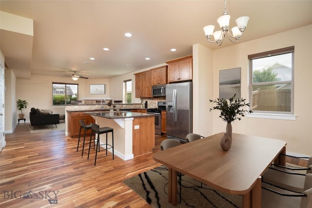 56 Koch Peak Ct, Bozeman, MT 59718 - kitchen featuring appliances with stainless steel finishes, light wood-style flooring, a breakfast bar area, recessed lighting, and brown cabinets