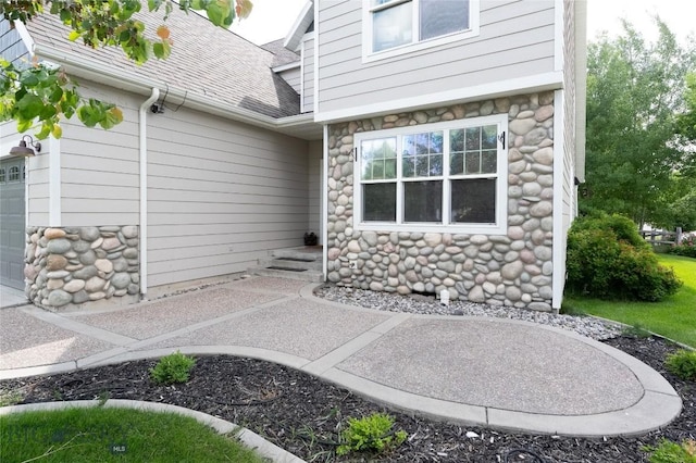 911 N Aster, Bozeman, MT 59718 - view of exterior entry with stone siding, a shingled roof, and a garage