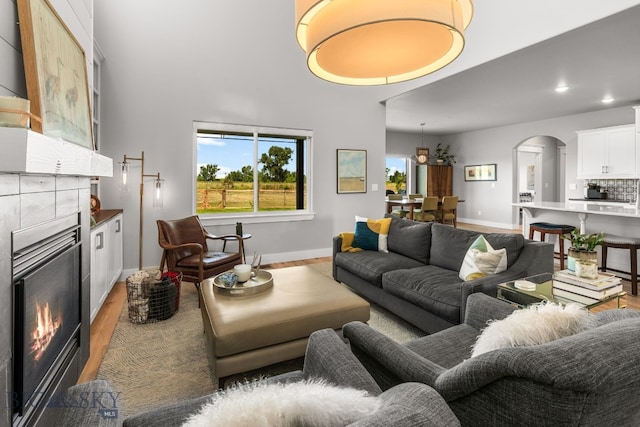 85 Riparian Way, Bozeman, MT 59718 - living room featuring a tiled fireplace, arched walkways, light wood finished floors, and recessed lighting