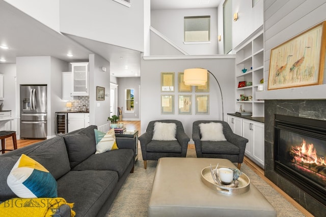 85 Riparian Way, Bozeman, MT 59718 - living area with beverage cooler, a high end fireplace, a high ceiling, built in features, and light wood-style floors