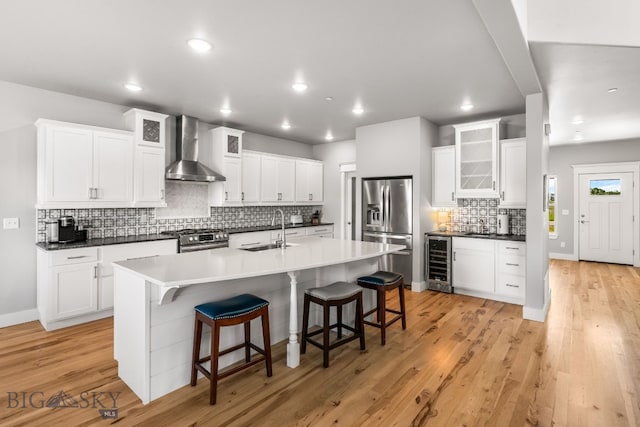 85 Riparian Way, Bozeman, MT 59718 - kitchen with wall chimney exhaust hood, appliances with stainless steel finishes, wine cooler, decorative backsplash, and a kitchen breakfast bar