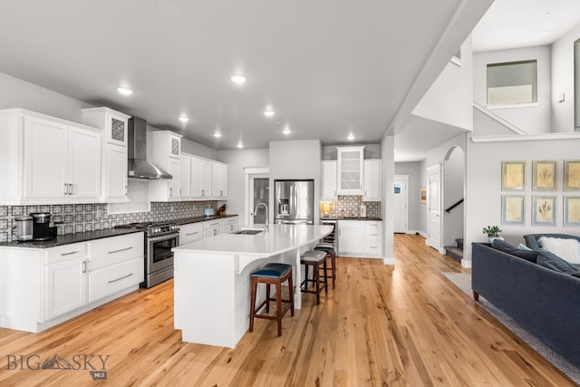 85 Riparian Way, Bozeman, MT 59718 - kitchen with appliances with stainless steel finishes, wall chimney range hood, a kitchen breakfast bar, glass insert cabinets, and tasteful backsplash