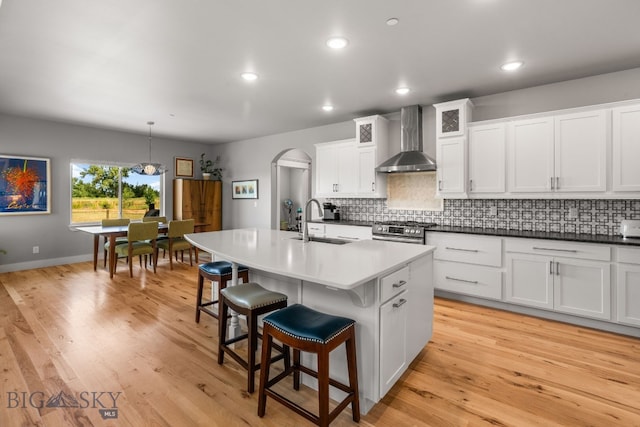 85 Riparian Way, Bozeman, MT 59718 - kitchen with wall chimney range hood, a kitchen breakfast bar, backsplash, arched walkways, and recessed lighting