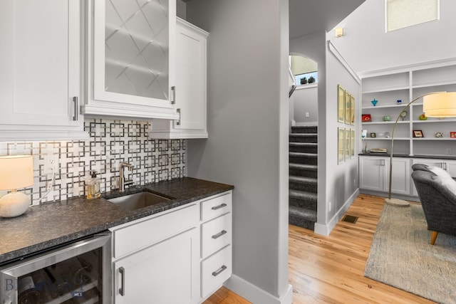 85 Riparian Way, Bozeman, MT 59718 - kitchen with beverage cooler, light wood-type flooring, white cabinets, and decorative backsplash
