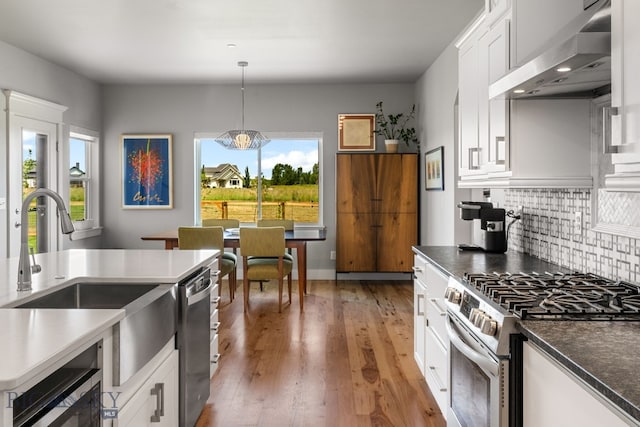 85 Riparian Way, Bozeman, MT 59718 - kitchen with wall chimney range hood, stainless steel appliances, backsplash, decorative light fixtures, and a chandelier