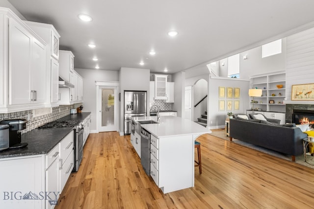 85 Riparian Way, Bozeman, MT 59718 - kitchen with stainless steel appliances, white cabinetry, tasteful backsplash, arched walkways, and a glass covered fireplace