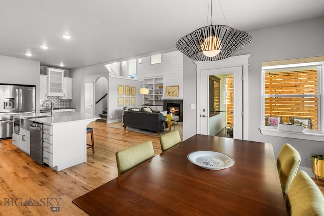 85 Riparian Way, Bozeman, MT 59718 - dining space with light wood-style flooring, recessed lighting, stairway, a warm lit fireplace, and arched walkways