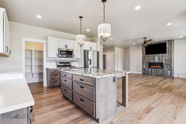 166 King Meadows Ln, Bozeman, MT 59718 - kitchen featuring stainless steel appliances, ceiling fan, a chandelier, light wood-style floors, and a large fireplace