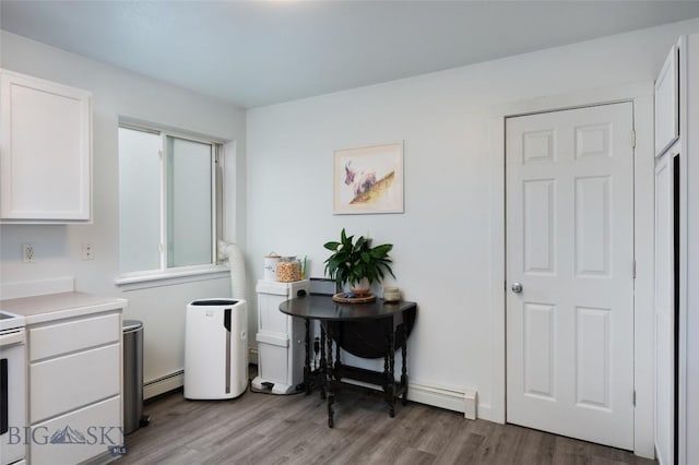 208 Show Pl Unit A, Belgrade, MT 59714 - kitchen featuring wood finished floors, a baseboard radiator, white cabinets, light countertops, and white electric range oven