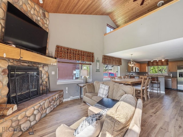 417 Firelight, Big Sky, MT 59716 - living area featuring a baseboard heating unit, wood finished floors, a stone fireplace, wooden ceiling, and lofted ceiling