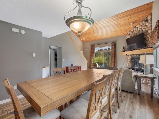 417 Firelight, Big Sky, MT 59716 - dining area featuring light wood-type flooring, a stone fireplace, and wood ceiling
