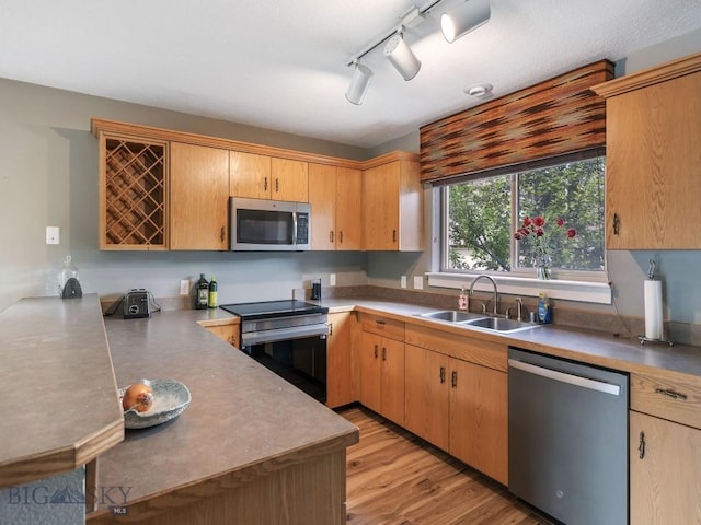 417 Firelight, Big Sky, MT 59716 - kitchen featuring appliances with stainless steel finishes, rail lighting, light wood-type flooring, a peninsula, and light countertops