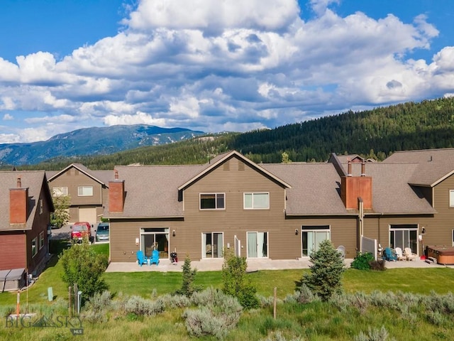 417 Firelight, Big Sky, MT 59716 - back of house featuring a chimney, a mountain view, a patio area, and a forest view