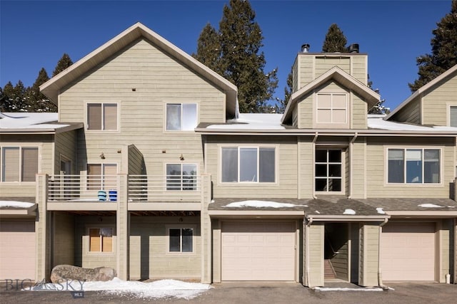 15 Spotted Fawn Ct, Big Sky, MT 59716 - snow covered house with a garage, a balcony, a chimney, and driveway