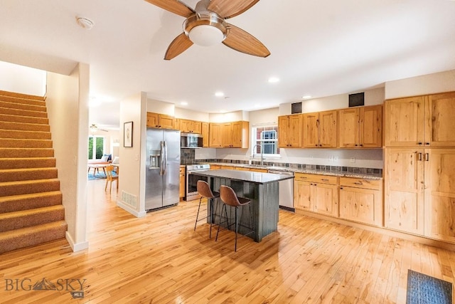 4619 Cascade St, Bozeman, MT 59718 - kitchen with appliances with stainless steel finishes, a kitchen bar, light wood-style floors, a center island, and recessed lighting