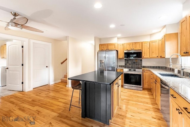 4619 Cascade St, Bozeman, MT 59718 - kitchen featuring stainless steel appliances, a breakfast bar area, light wood-type flooring, light brown cabinetry, and recessed lighting