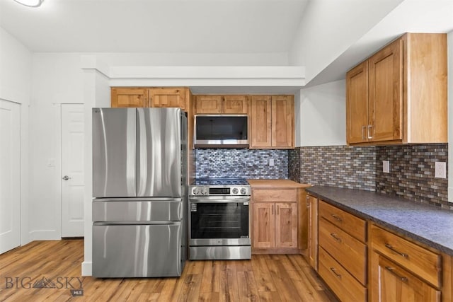 4901 Itana Cir, Bozeman, MT 59715 - kitchen with appliances with stainless steel finishes, light wood-style flooring, backsplash, dark countertops, and brown cabinets