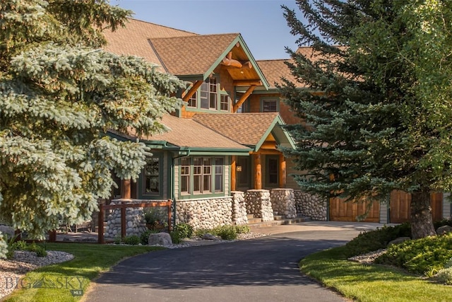 390 Hayrake Ln, Bozeman, MT 59715 - view of front of property with driveway, stone siding, a shingled roof, and a porch