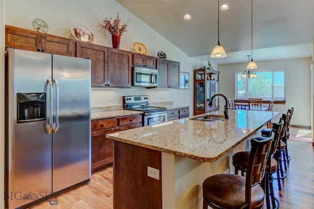 9848 Durston Rd Unit A, Bozeman, MT 59718 - kitchen featuring stainless steel appliances, light wood-style flooring, lofted ceiling, a center island with sink, and a kitchen breakfast bar