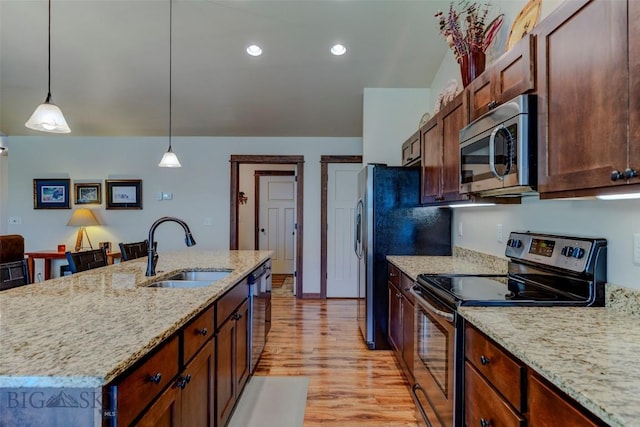 9848 Durston Rd Unit A, Bozeman, MT 59718 - kitchen featuring stainless steel appliances, light wood-type flooring, hanging light fixtures, light stone counters, and a kitchen island with sink