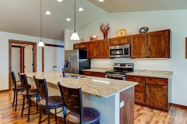 9848 Durston Rd Unit A, Bozeman, MT 59718 - kitchen with stainless steel appliances, vaulted ceiling, light wood-style flooring, a kitchen bar, and a kitchen island with sink