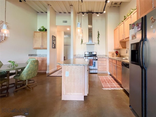 140 Village Crossing Way Unit 1J, Bozeman, MT 59715 - kitchen featuring appliances with stainless steel finishes, light brown cabinetry, concrete flooring, wall chimney range hood, and a towering ceiling