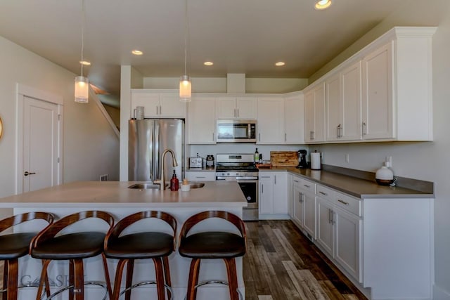2002 Chipset St Unit A, Bozeman, MT 59718 - kitchen featuring appliances with stainless steel finishes, white cabinetry, a breakfast bar, dark wood-style floors, and a center island with sink