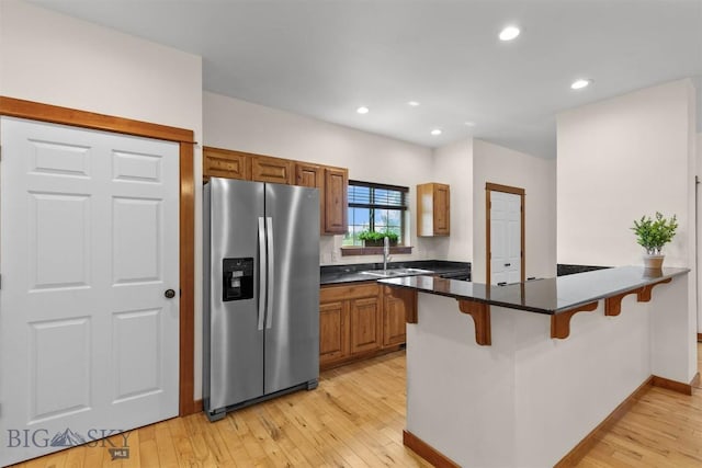 332 N Cottonwood Rd Unit F, Bozeman, MT 59718 - kitchen with stainless steel fridge, a peninsula, a breakfast bar, light wood-type flooring, and brown cabinets