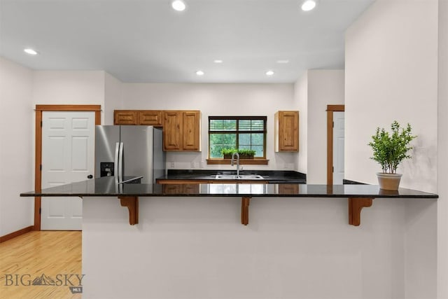 332 N Cottonwood Rd Unit F, Bozeman, MT 59718 - kitchen featuring stainless steel fridge, a breakfast bar area, light wood-type flooring, recessed lighting, and brown cabinets