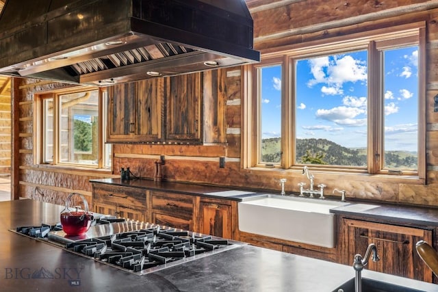 94 Sky Band Trl, Livingston, MT 59047 - kitchen featuring wall chimney range hood, dark countertops, stainless steel gas stovetop, and wooden walls