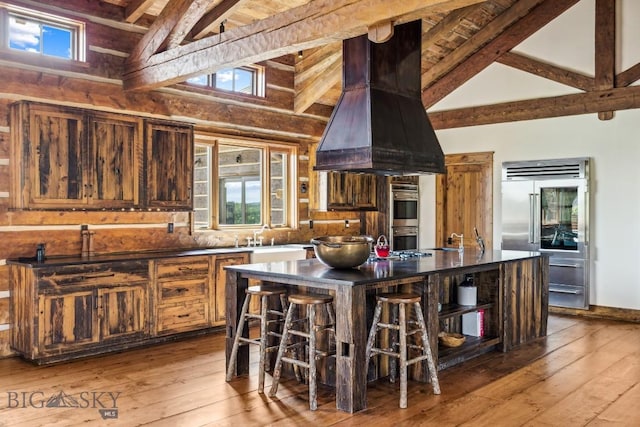 94 Sky Band Trl, Livingston, MT 59047 - kitchen featuring range hood, appliances with stainless steel finishes, wood-type flooring, dark countertops, and high vaulted ceiling