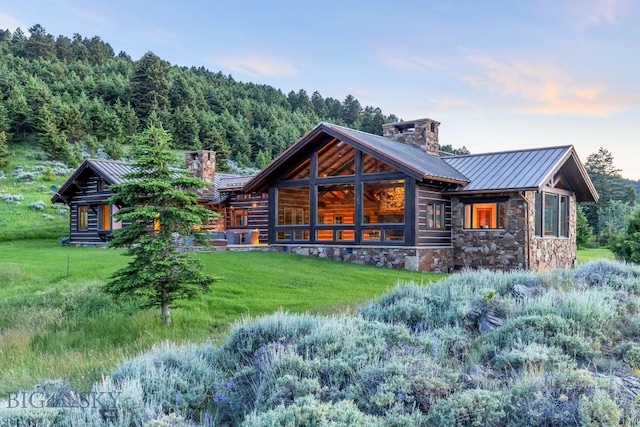 94 Sky Band Trl, Livingston, MT 59047 - back of house featuring a chimney, a standing seam roof, a metal roof, a lawn, and stone siding