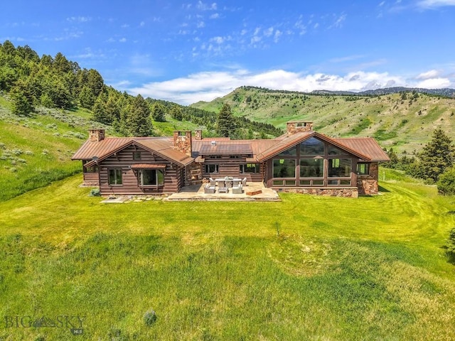 94 Sky Band Trl, Livingston, MT 59047 - back of property featuring a chimney, a patio, a yard, a metal roof, and a mountain view