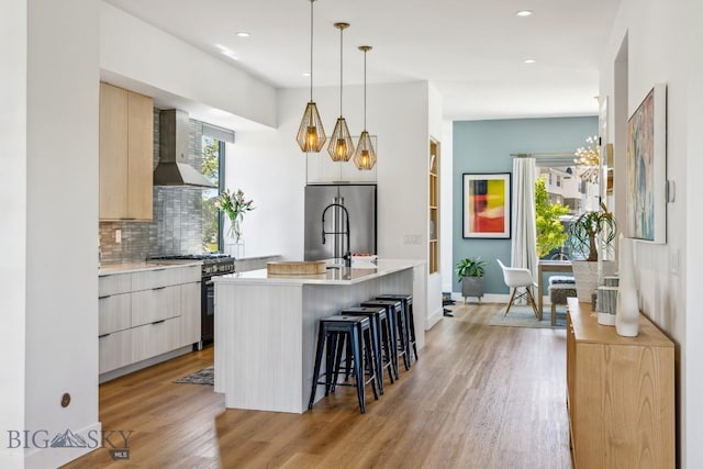 1492 Windrow Dr, Bozeman, MT 59718 - kitchen with range with gas cooktop, stainless steel fridge, modern cabinets, wall chimney exhaust hood, and light wood finished floors