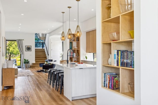 1492 Windrow Dr, Bozeman, MT 59718 - kitchen with modern cabinets, light wood-style floors, a breakfast bar, decorative light fixtures, and recessed lighting