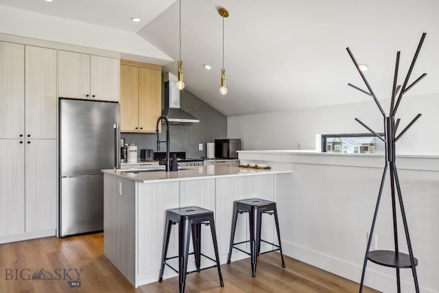 1492 Windrow Dr, Bozeman, MT 59718 - kitchen featuring stainless steel refrigerator, wall chimney range hood, lofted ceiling, light countertops, and light wood-type flooring