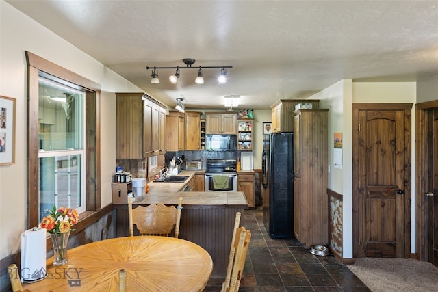 120 N Pine Butte, Bozeman, MT 59718 - kitchen featuring black appliances, a peninsula, decorative backsplash, and dark stone finish floors