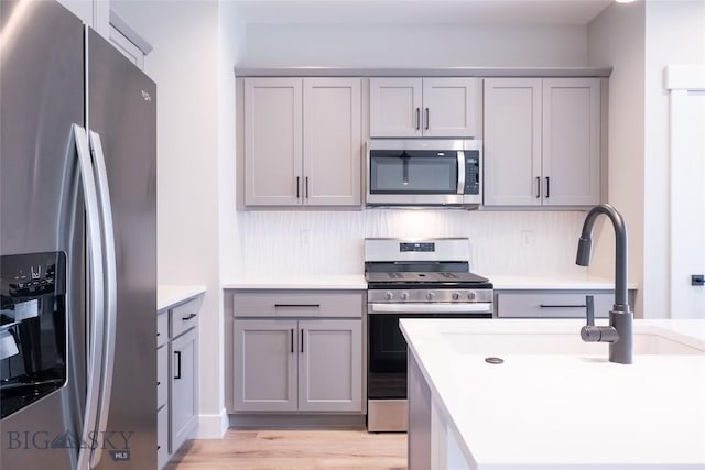 740 Rogers Way Unit A, Bozeman, MT 59718 - kitchen with appliances with stainless steel finishes, gray cabinetry, light wood finished floors, and light countertops