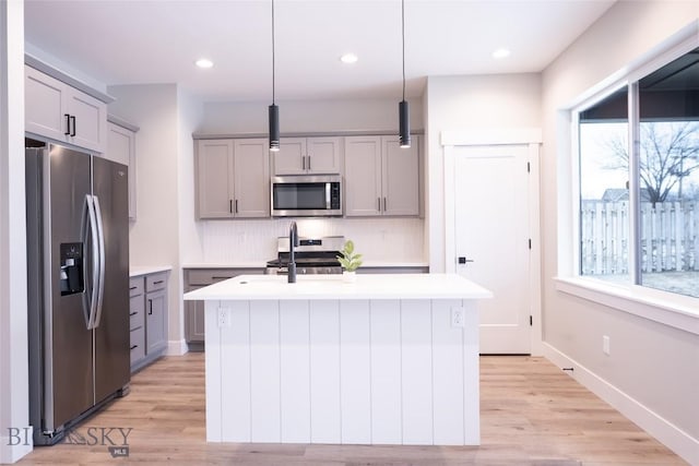 740 Rogers Way Unit A, Bozeman, MT 59718 - kitchen featuring appliances with stainless steel finishes, gray cabinets, light countertops, an island with sink, and light wood-style flooring