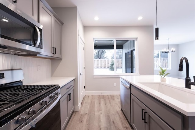 740 Rogers Way Unit A, Bozeman, MT 59718 - kitchen with appliances with stainless steel finishes, gray cabinetry, light wood-type flooring, a chandelier, and recessed lighting