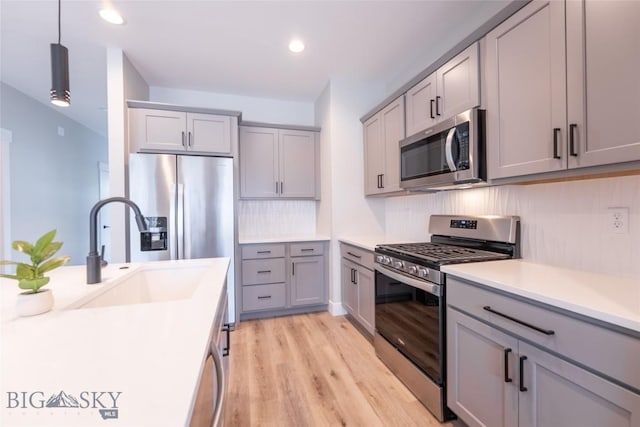 740 Rogers Way Unit A, Bozeman, MT 59718 - kitchen featuring appliances with stainless steel finishes, gray cabinets, light wood-style flooring, light countertops, and tasteful backsplash