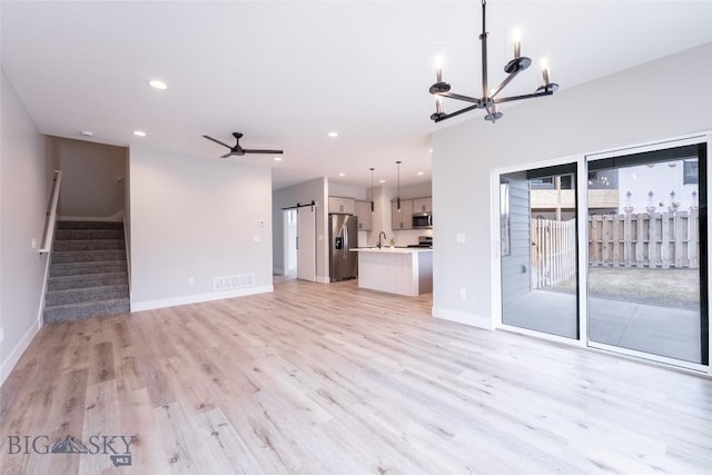 740 Rogers Way Unit A, Bozeman, MT 59718 - unfurnished living room with a chandelier, light wood-type flooring, stairs, a barn door, and recessed lighting