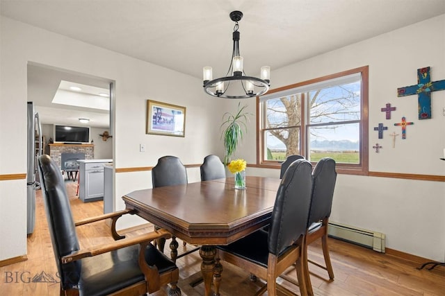 109 Cottonwood St, Manhattan, MT 59741 - dining area with a baseboard radiator, light wood-style flooring, a chandelier, and a fireplace