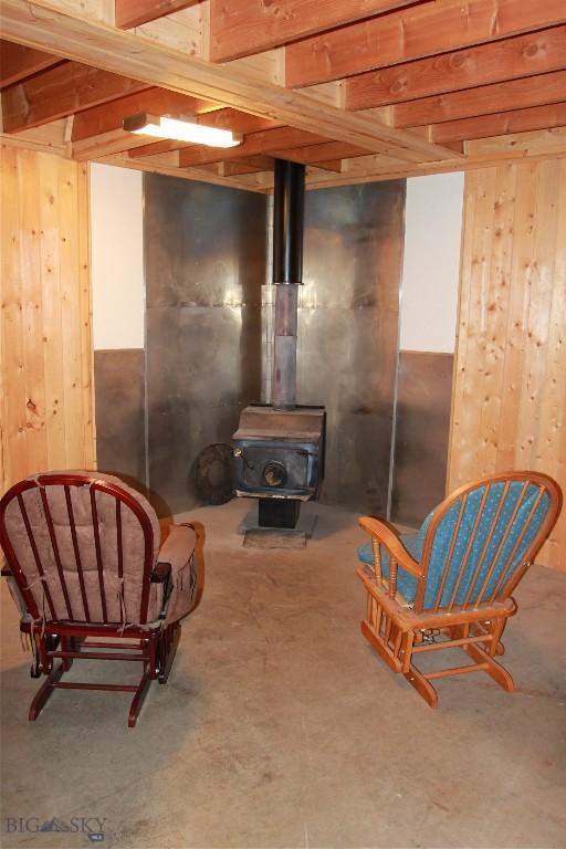 524 Grizzly Meadow Rd, Emigrant, MT 59027 - living area featuring wood walls, a wood stove, and unfinished concrete floors